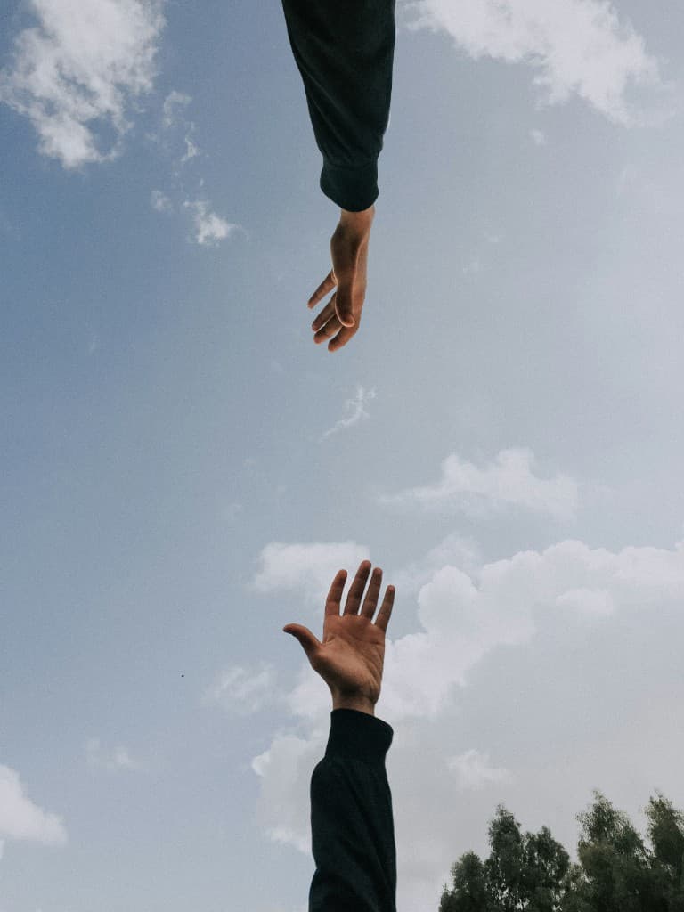 Two hands reaching toward each other in a gesture of support and connection